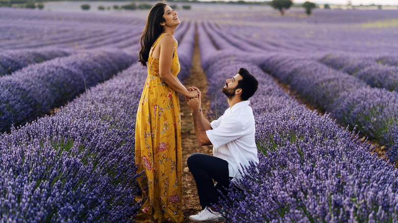 man proposing to woman in field