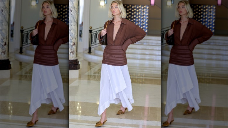 woman in brown shirt, white skirt, and suede mules