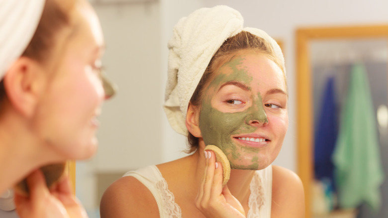 woman applying face mask in mirror