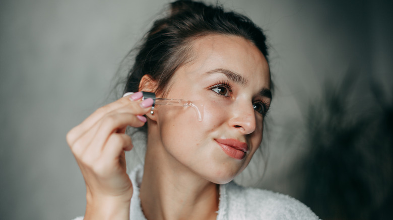 Woman applies serum to face