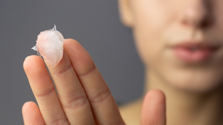 Woman holds up moisturizing balm 