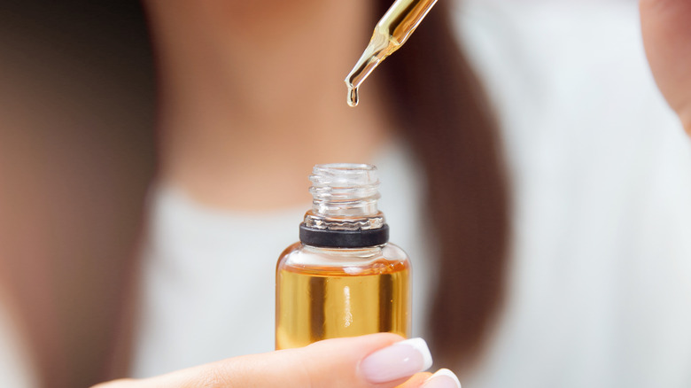 woman holding bottle containing oil