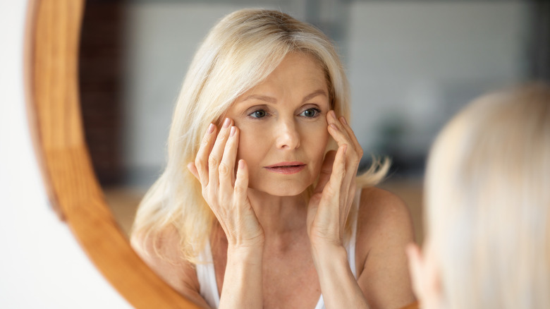 Woman looking at her face in mirror