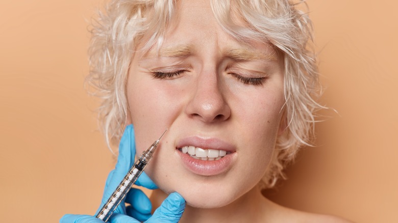 Woman in pain getting fillers