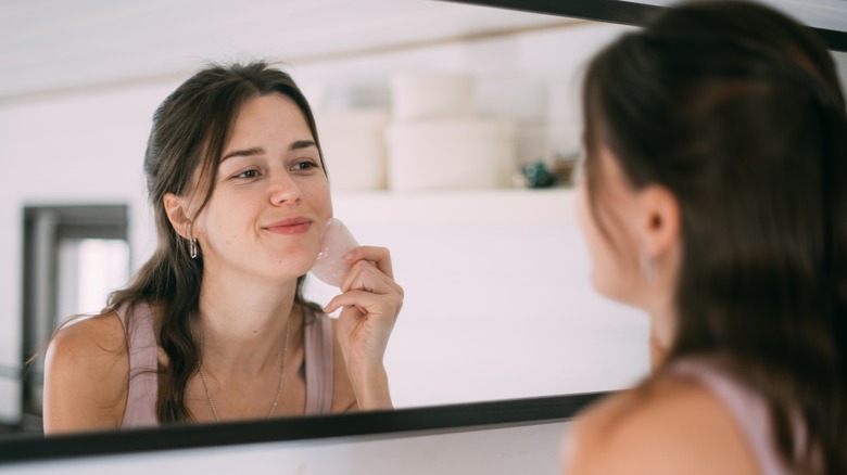 woman doing gua sha in mirror