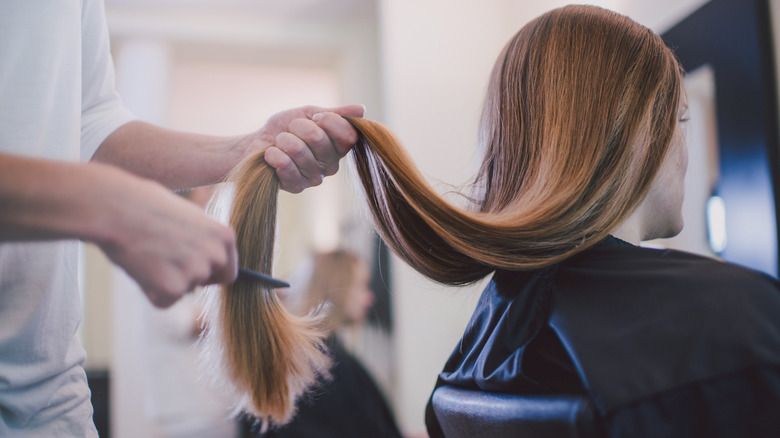 A woman getting long hair cut