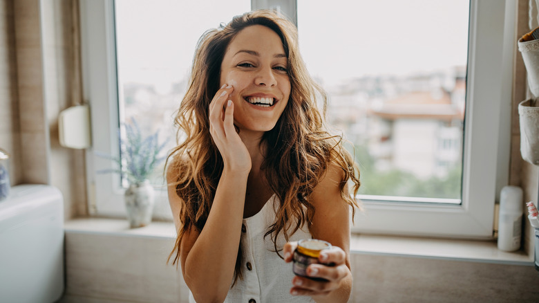 smiling woman applying face product