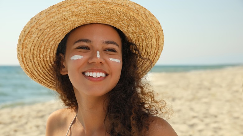 A woman wearing a hat and SPF on the beach
