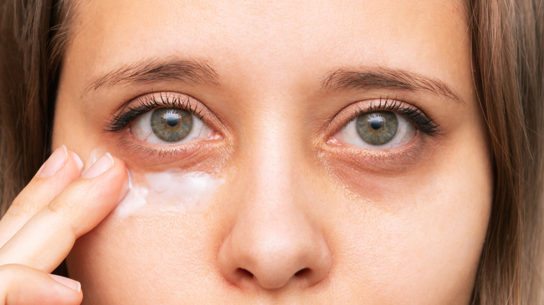 A woman applying eye cream