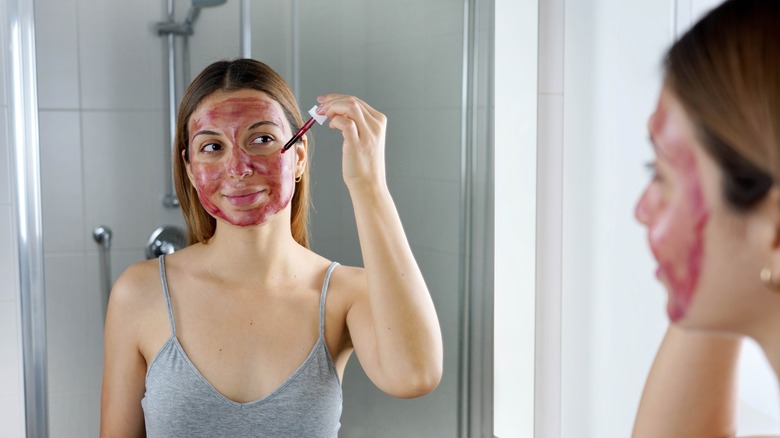 A woman applying a red exfoliating serum to her face