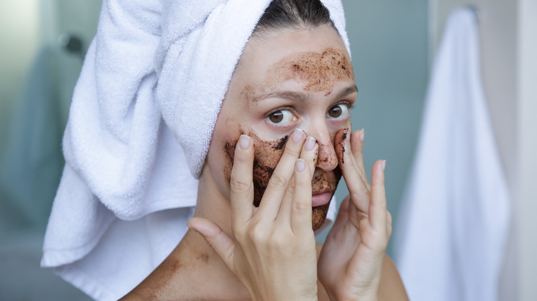 woman scrubbing face with scrub