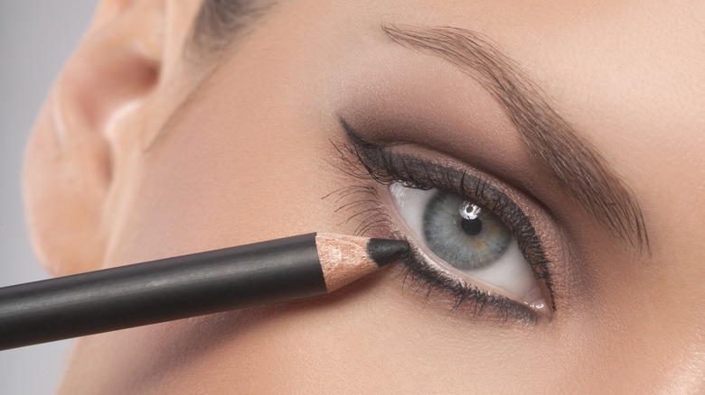 woman applying pencil liner