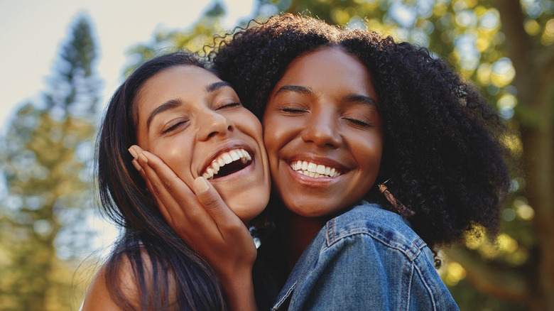 two smiling women hugging outside