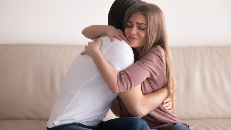 Couple hugging goodbye on sofa