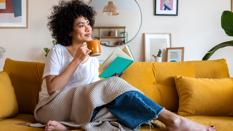 Woman happily reading book on sofa