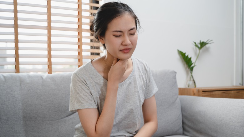 Woman touches sore neck