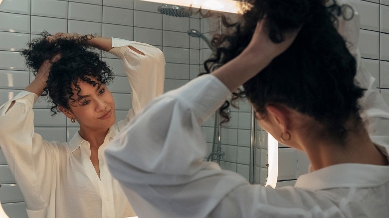 Woman putting hair up in mirror