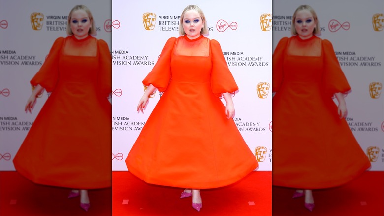 Nicola Coughlan wearing a bright orange dress on the red carpet.