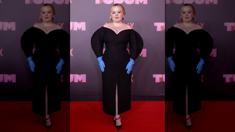 Nicola Coughlan wearing a black dress with bright blue gloves.