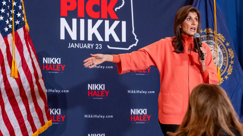 Nikki Haley wearing a salmon jacket and turtleneck set on stage.