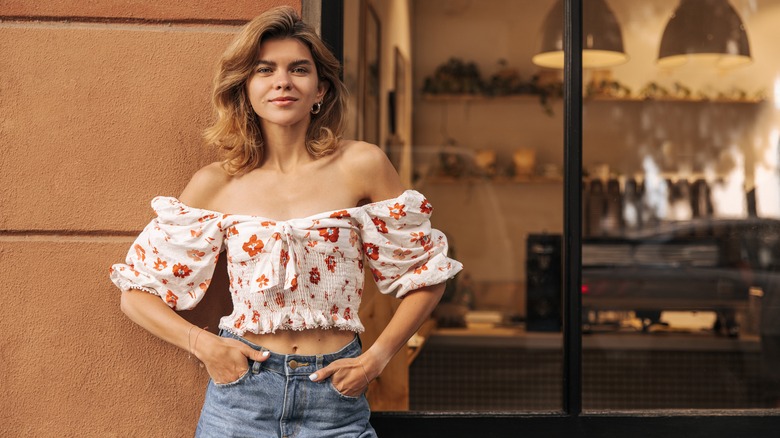 Woman wearing off-the-shoulder floral blouse, jeans