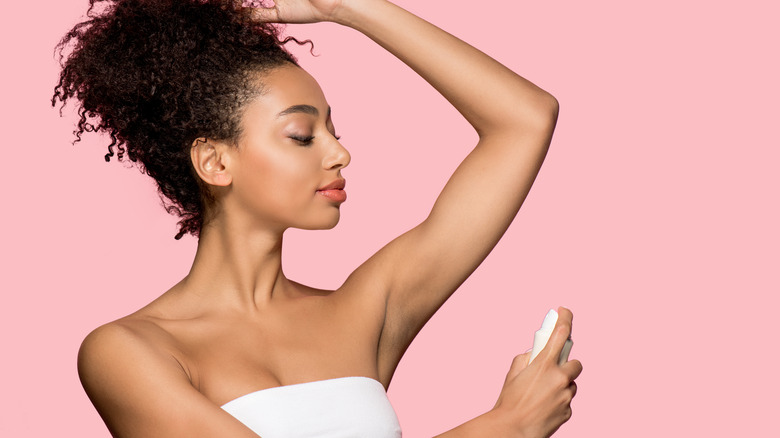 Woman using spray deodorant.