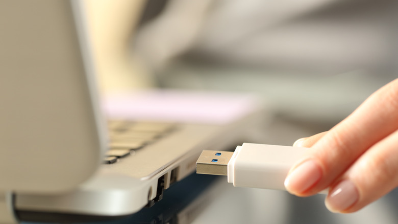 woman connecting USB cable to laptop