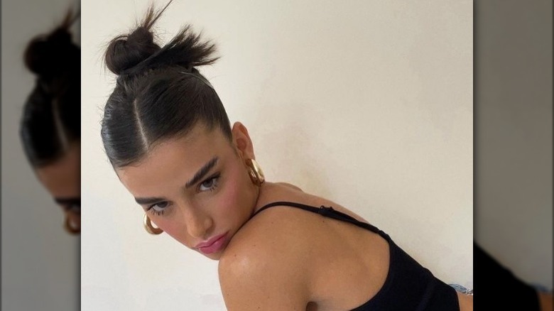 Woman wears high slicked-back bun with center part