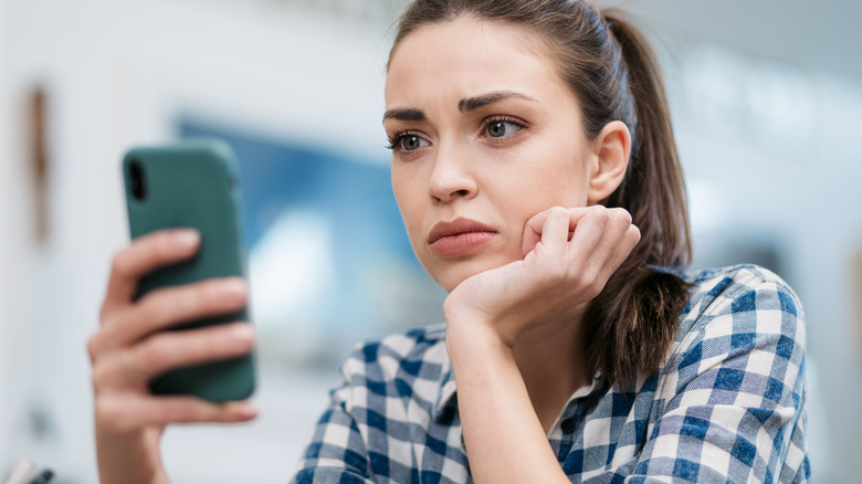 Woman frowning at cell phone