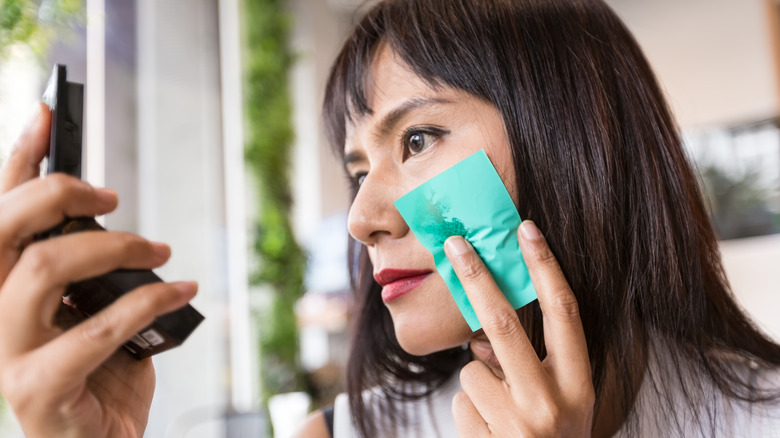 woman using oil blotting sheet