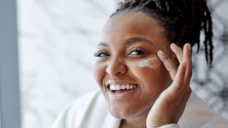 smiling woman applying skincare product