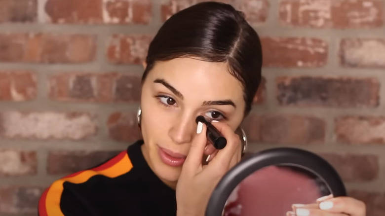 Olivia Culpo applying concealer