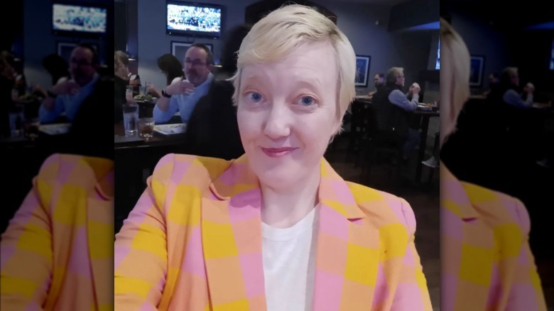 Woman poses in pink and yellow blazer with shoulder pads