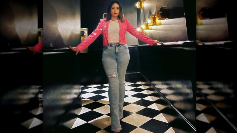 Woman poses in pink mini jacket with shoulder pads