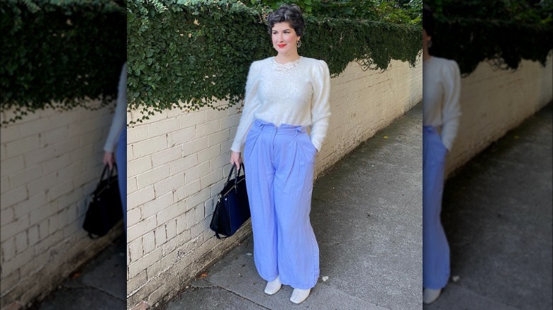 Woman poses in wide legged pants and puff sleeved sweater