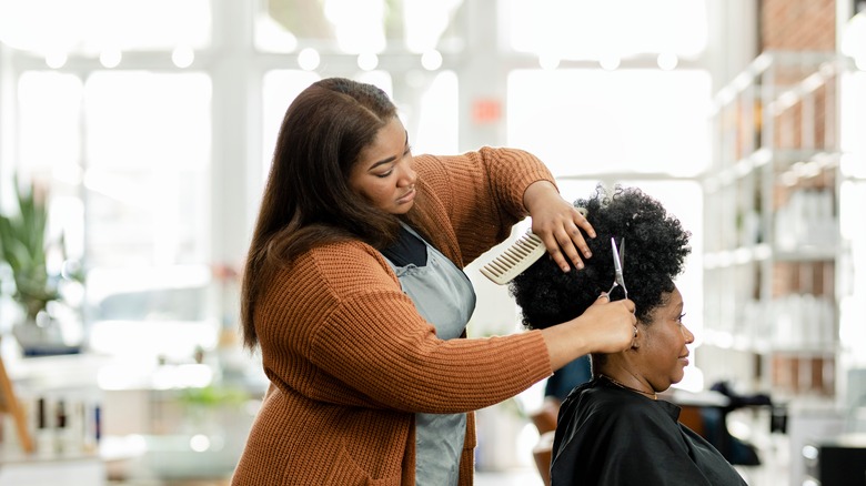 hairstylist cutting woman's curly hair