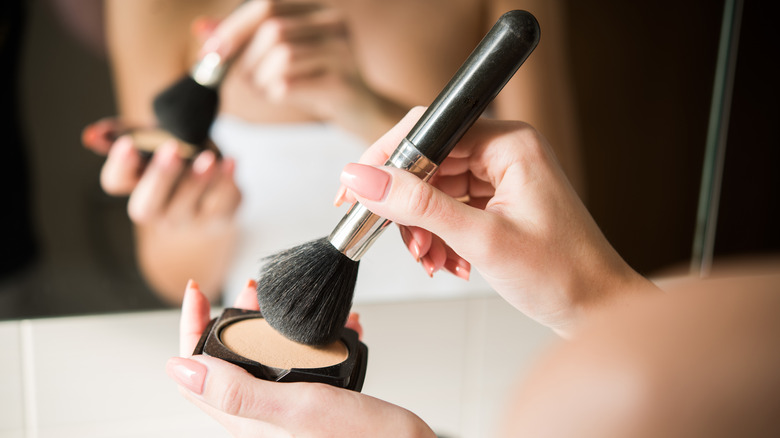 Woman dipping makeup brush in foundation