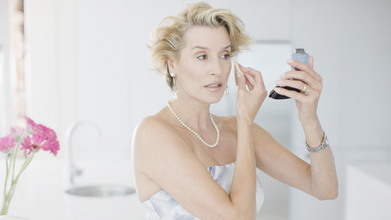 Older woman applying makeup
