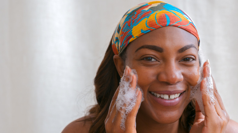 A woman cleaning her face with soapy cleanser