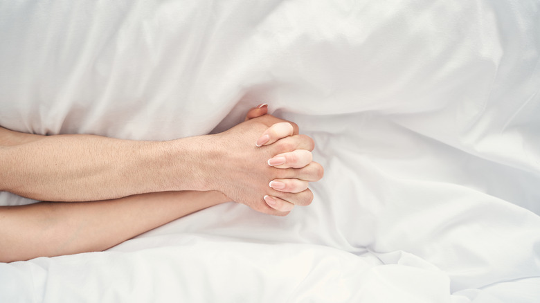 Couple holding hands on bed