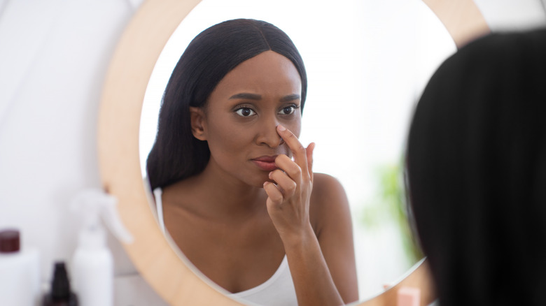Woman looking at nose in mirror