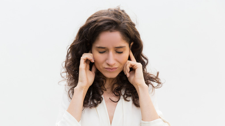 A woman plugging her ears