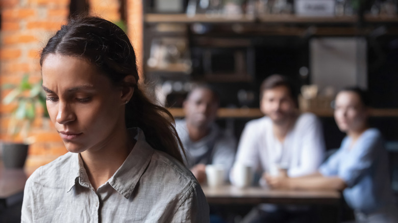 woman sitting away from group