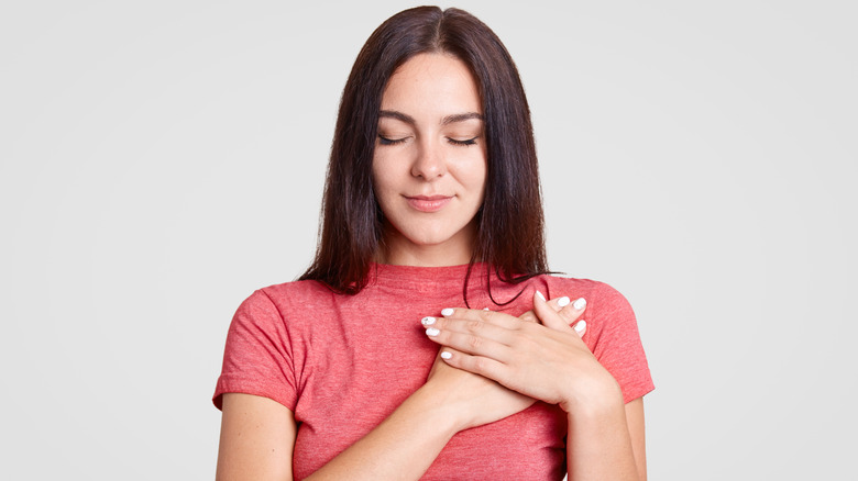 woman holding hand to chest