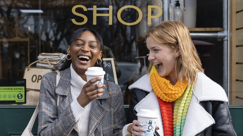 Friends laughing outside coffee shop