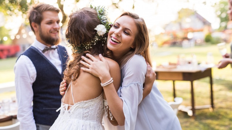 Wedding guest hugging bride