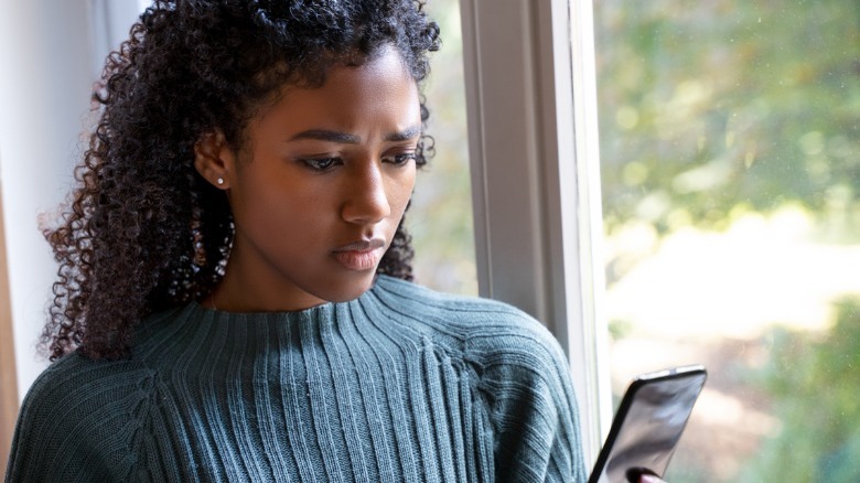 Uncertain woman looking at phone