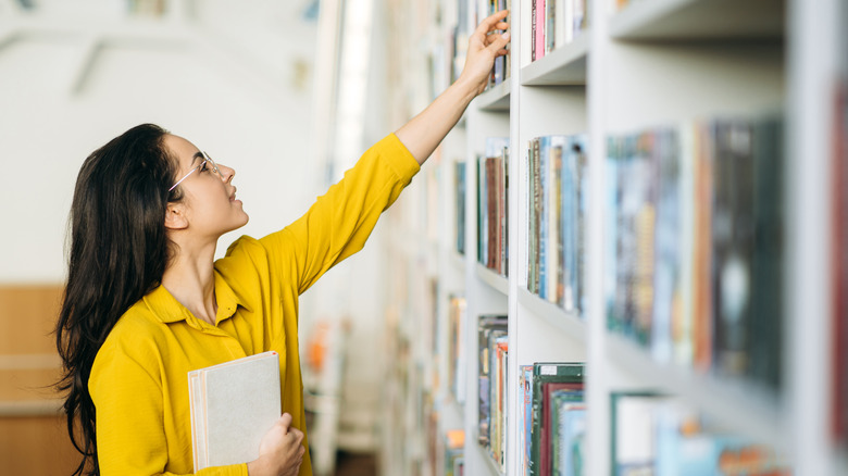 Woman reaching up for books