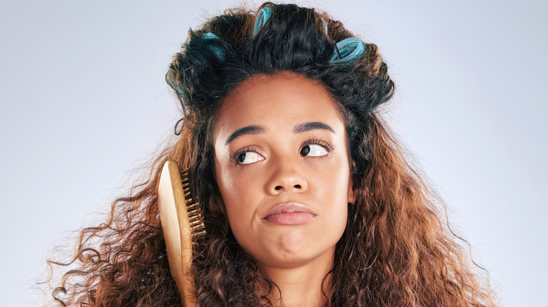 Upset woman with curlers, brush