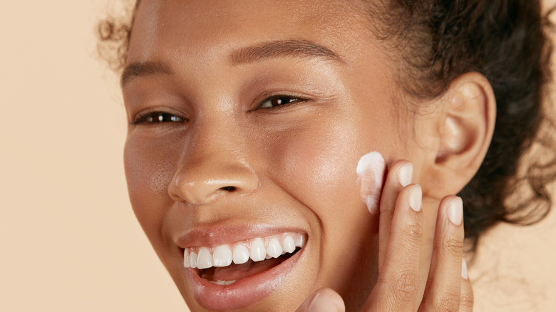 woman applying cream on cheek